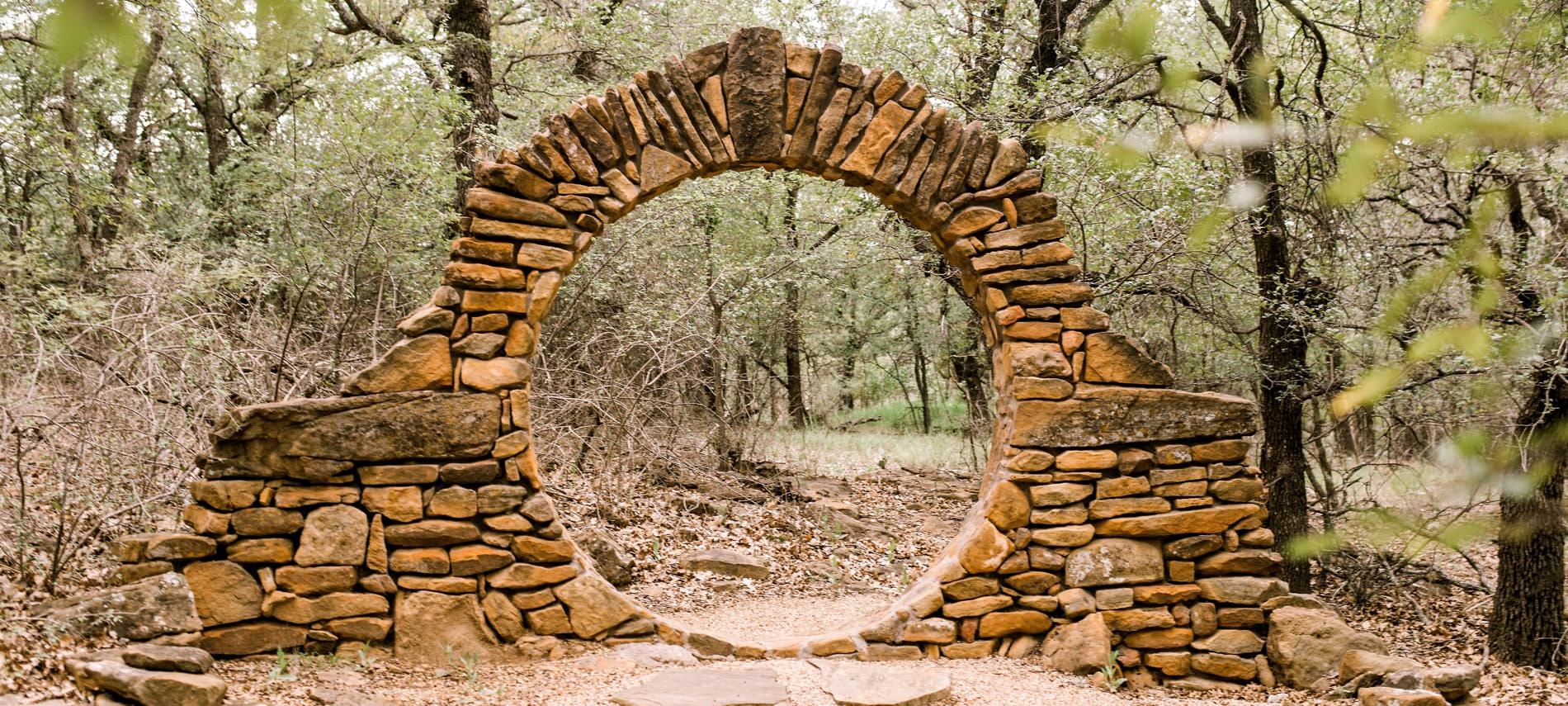 Handmade stone arch with base at the entrance of the woods